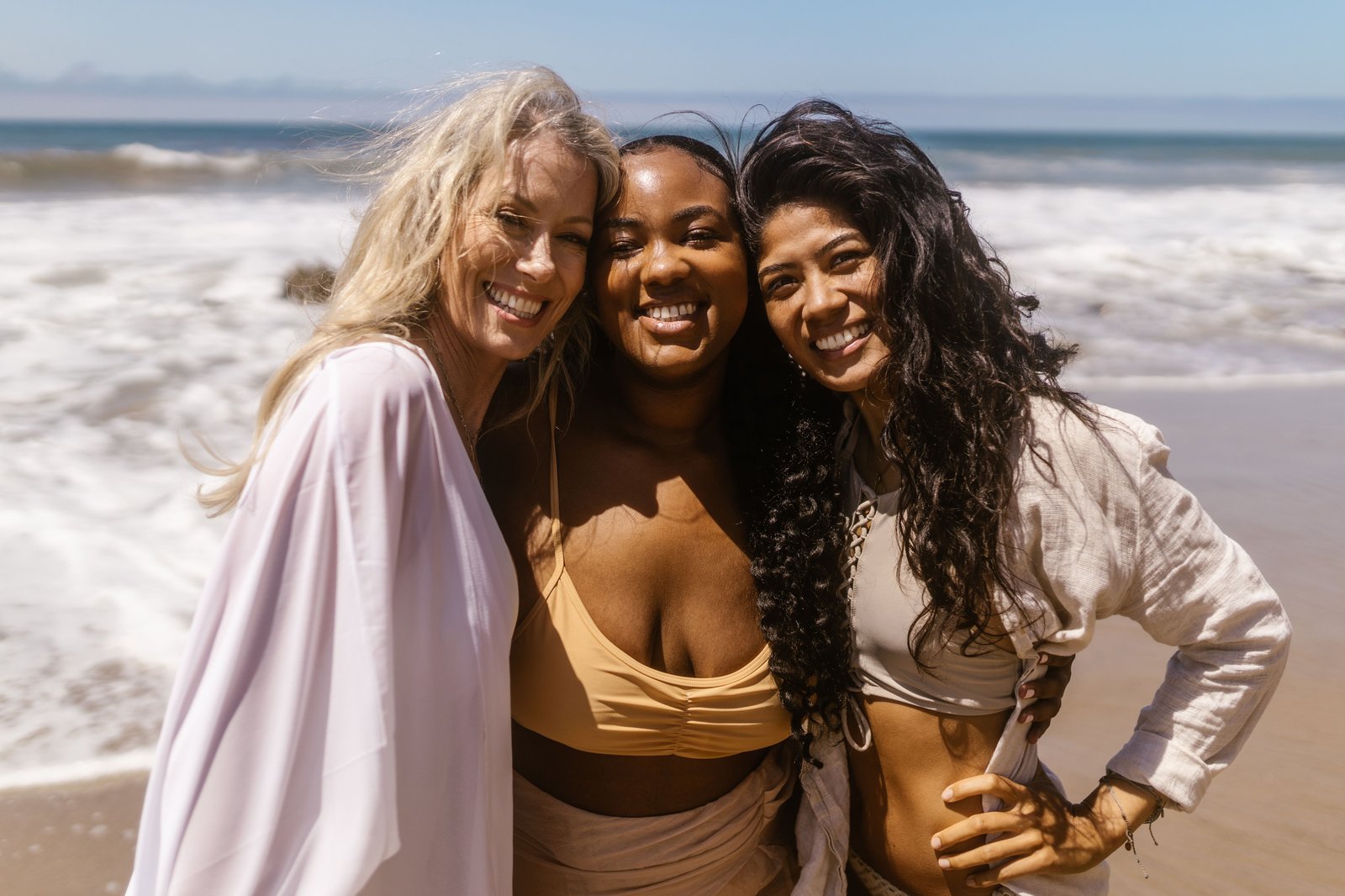 Three friends smiling together on the beach